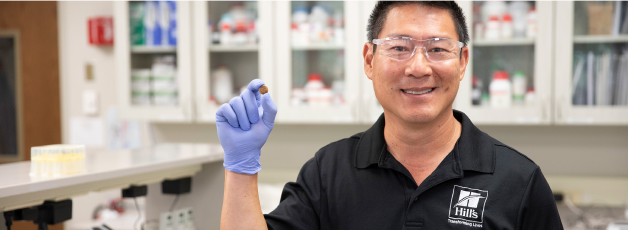 Výskumník spoločnosti Hill's držiaci granule krmiva Hill's v ruke